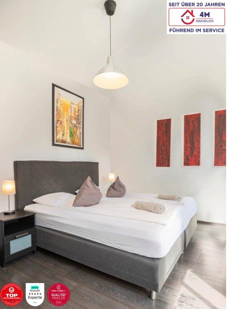 Freundliches Schlafzimmer mit Doppelbett, Nachttischen und dekorativen roten Wandbildern.