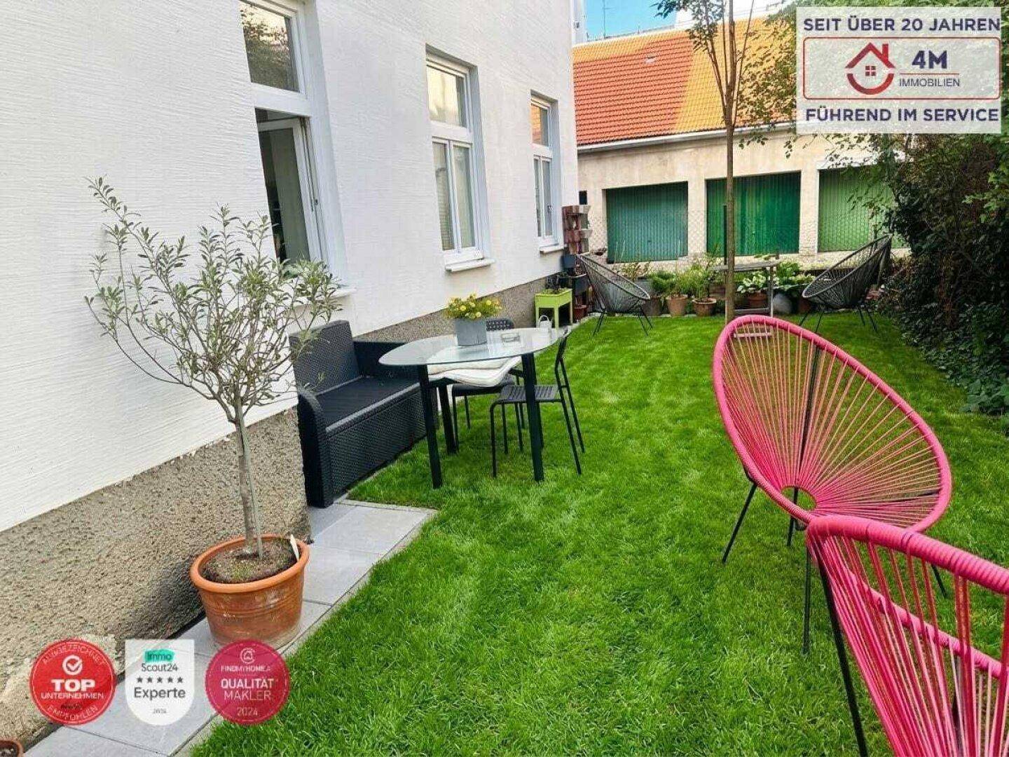 Kleiner, gepflegter Gartenbereich mit Rasenfläche, Sitzgelegenheiten und bunten Stühlen.