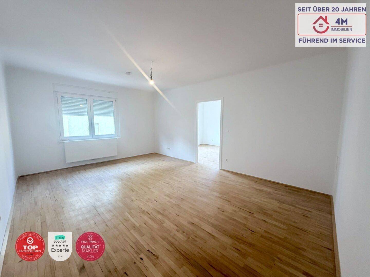 Leeres Zimmer mit hellem Parkettboden und einem Fenster, bereit für neue Bewohner.
