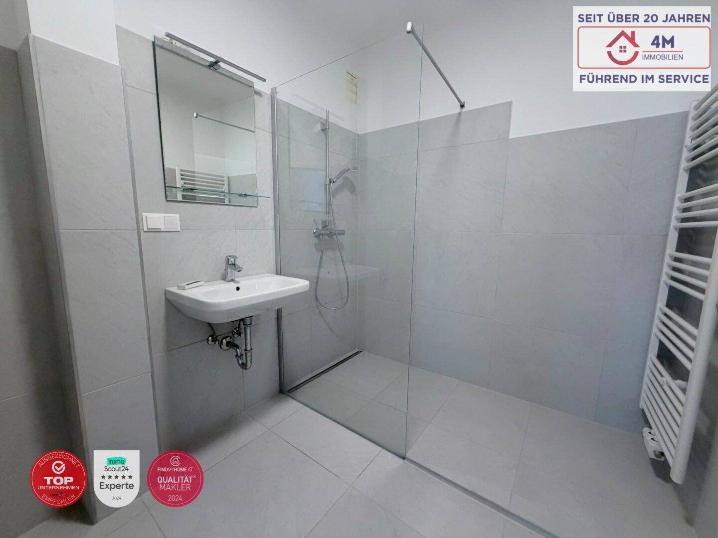 Modernes Badezimmer mit ebenerdiger Dusche, Waschbecken und beheiztem Handtuchhalter.