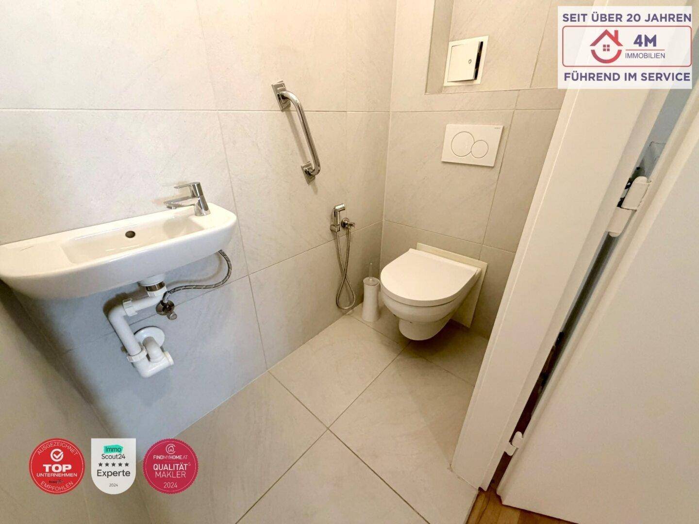 Gäste-WC mit Wand-WC, kleinem Waschbecken und Haltegriffen für zusätzliche Sicherheit.
