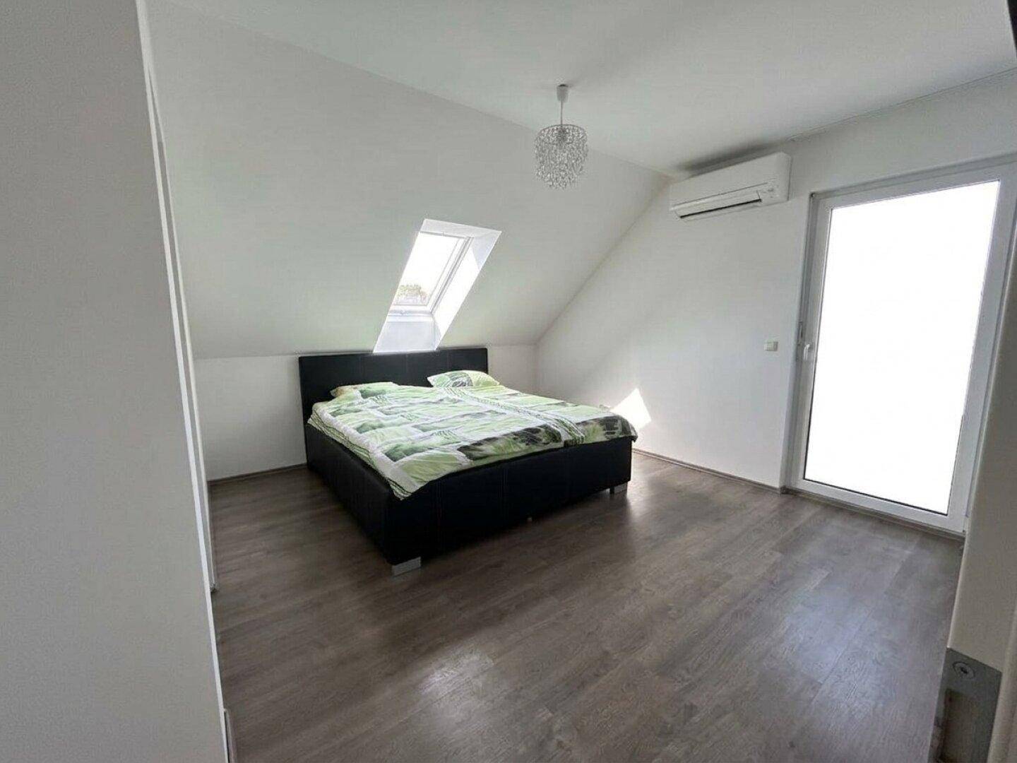 Gemütliches Schlafzimmer im Dachgeschoss mit Doppelbett, Dachfenster und Klimaanlage.