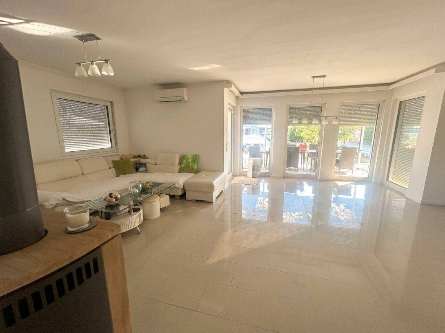 Geräumiges Wohnzimmer mit bequemer Couch, Kaminofen und direktem Zugang zur sonnigen Terrasse.