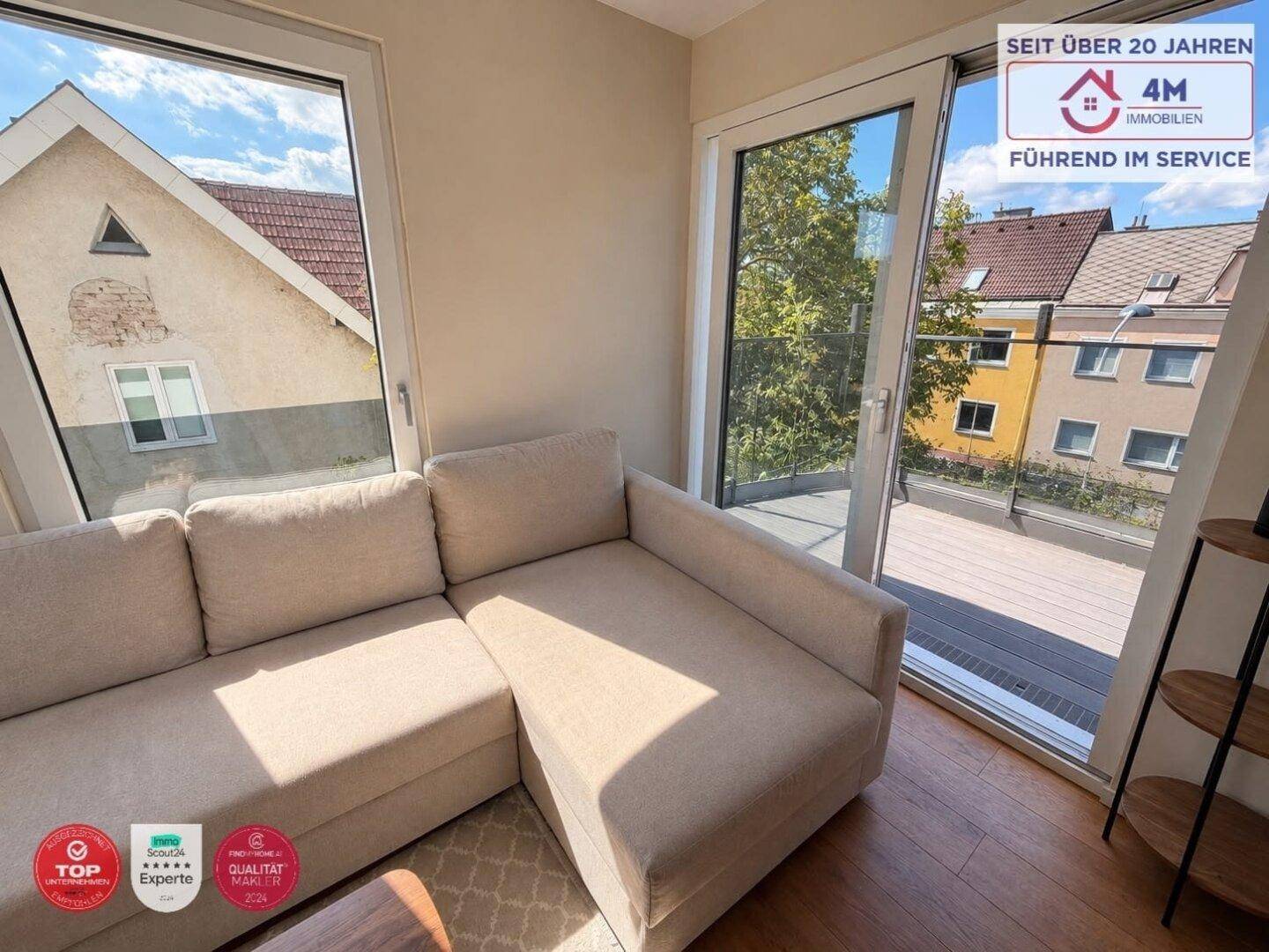 Gemütlicher Wohnbereich mit beigem Sofa und großen Fenstern mit Blick auf die Umgebung.