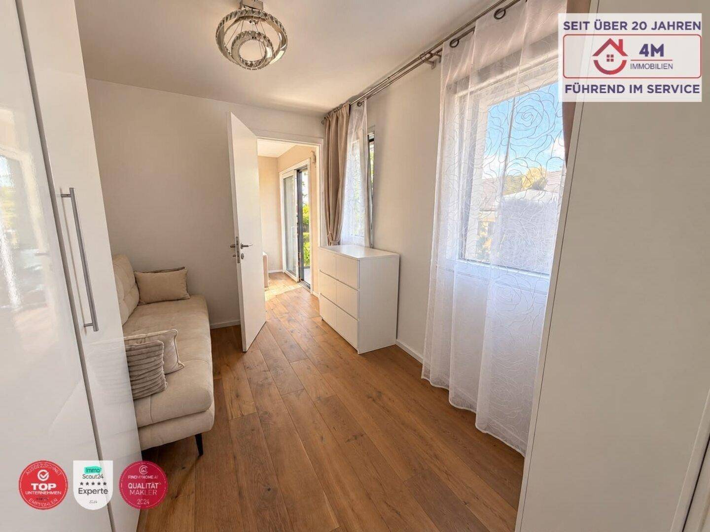 Helles Schlafzimmer mit Holzboden, weißem Kleiderschrank und Zugang zu einem Außenbereich.