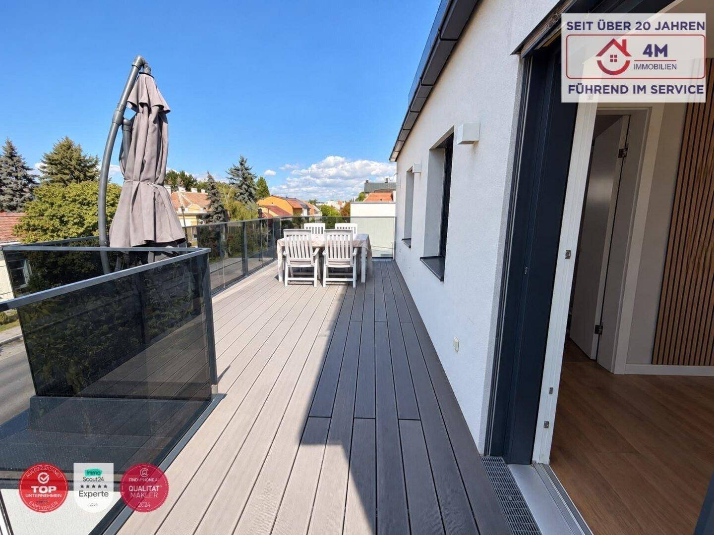 Geräumige Dachterrasse mit Holzdeck, Gartenmöbeln und Sonnenschirm für entspannte Stunden.