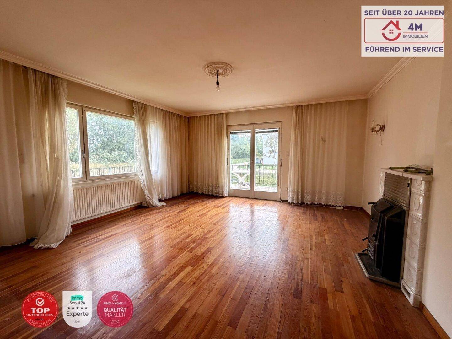 Geräumiges Wohnzimmer mit Parkettboden, Kamin und Zugang zur Terrasse.