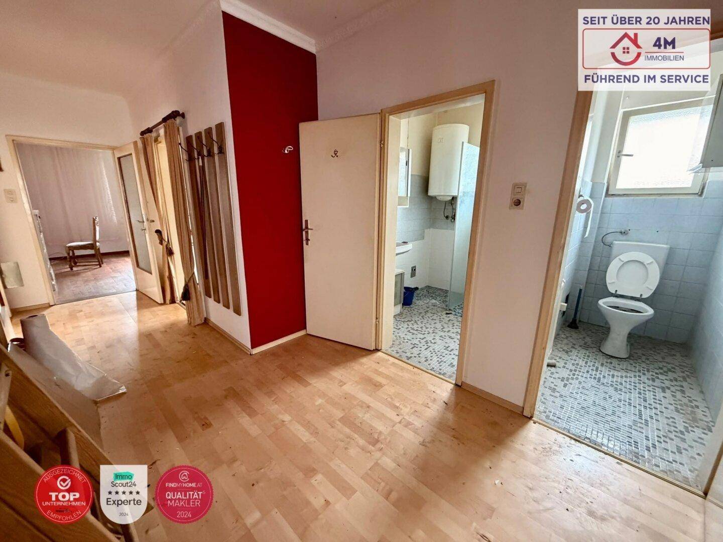 Flur mit Zugang zu Badezimmer und separatem WC, akzentuiert durch eine rote Wand.