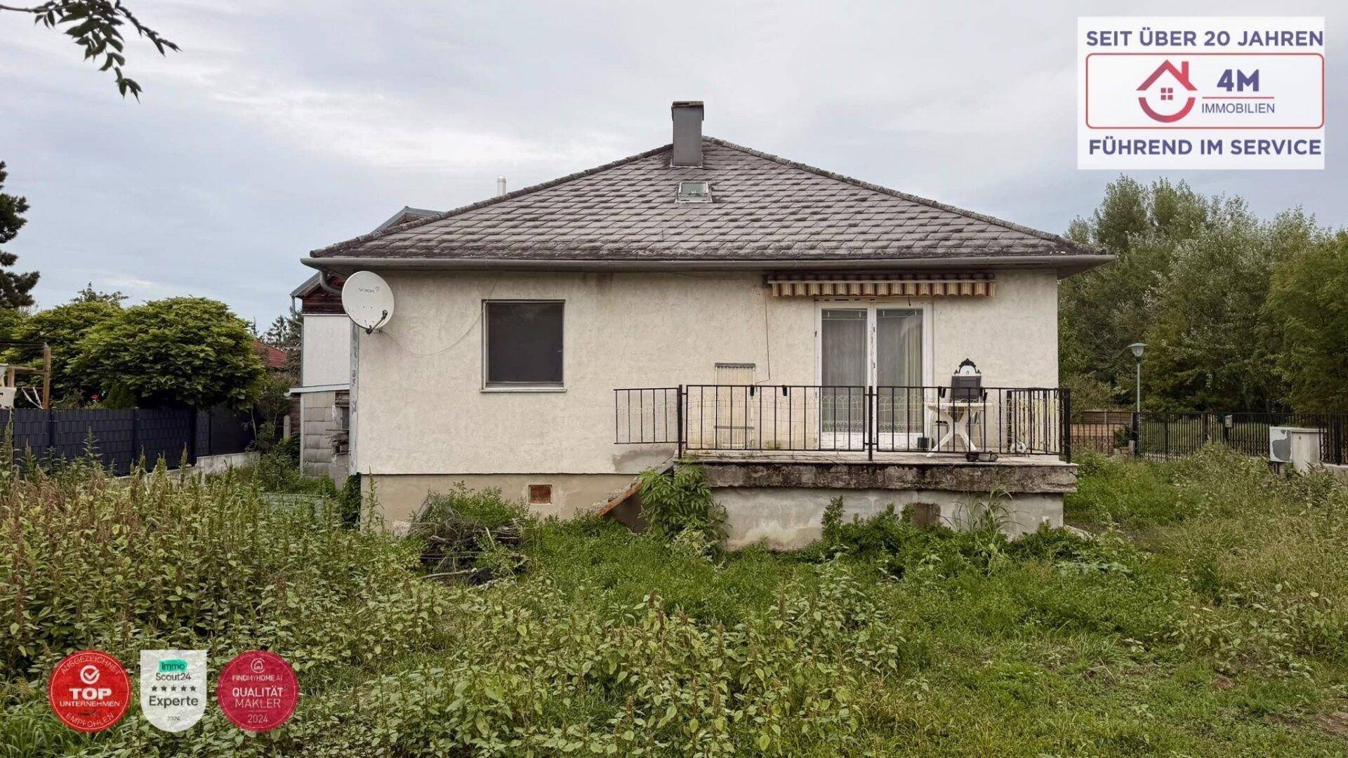 Rückansicht des Hauses mit Terrasse und einem ungepflegten Gartenbereich.