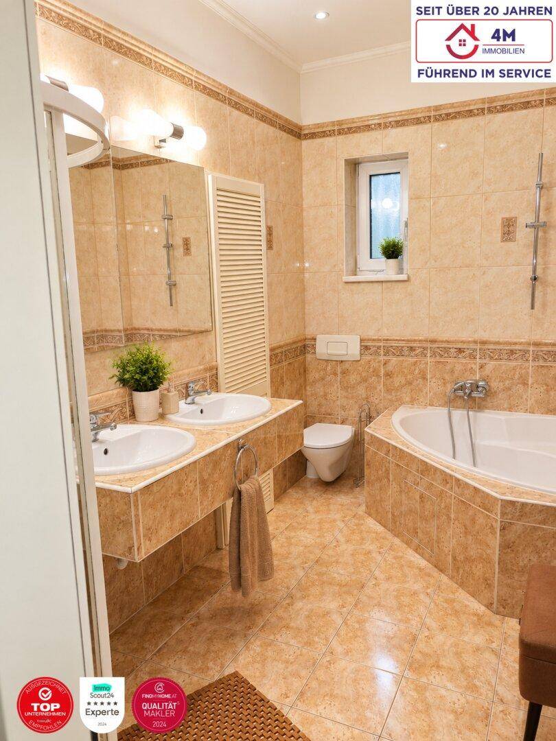 Geräumiges Badezimmer mit Badewanne, Doppelwaschbecken, WC und Fenster.