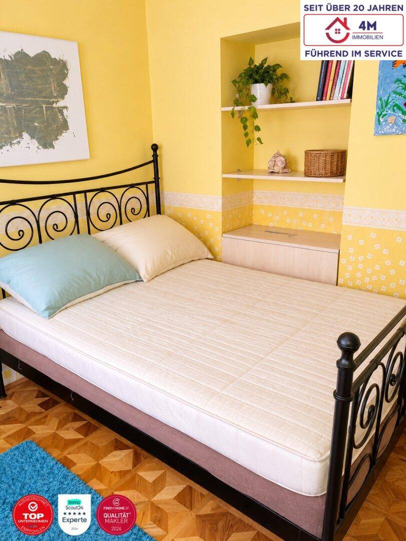 Schlafzimmer mit Einzelbett, Parkettboden und integrierten Wandregalen.