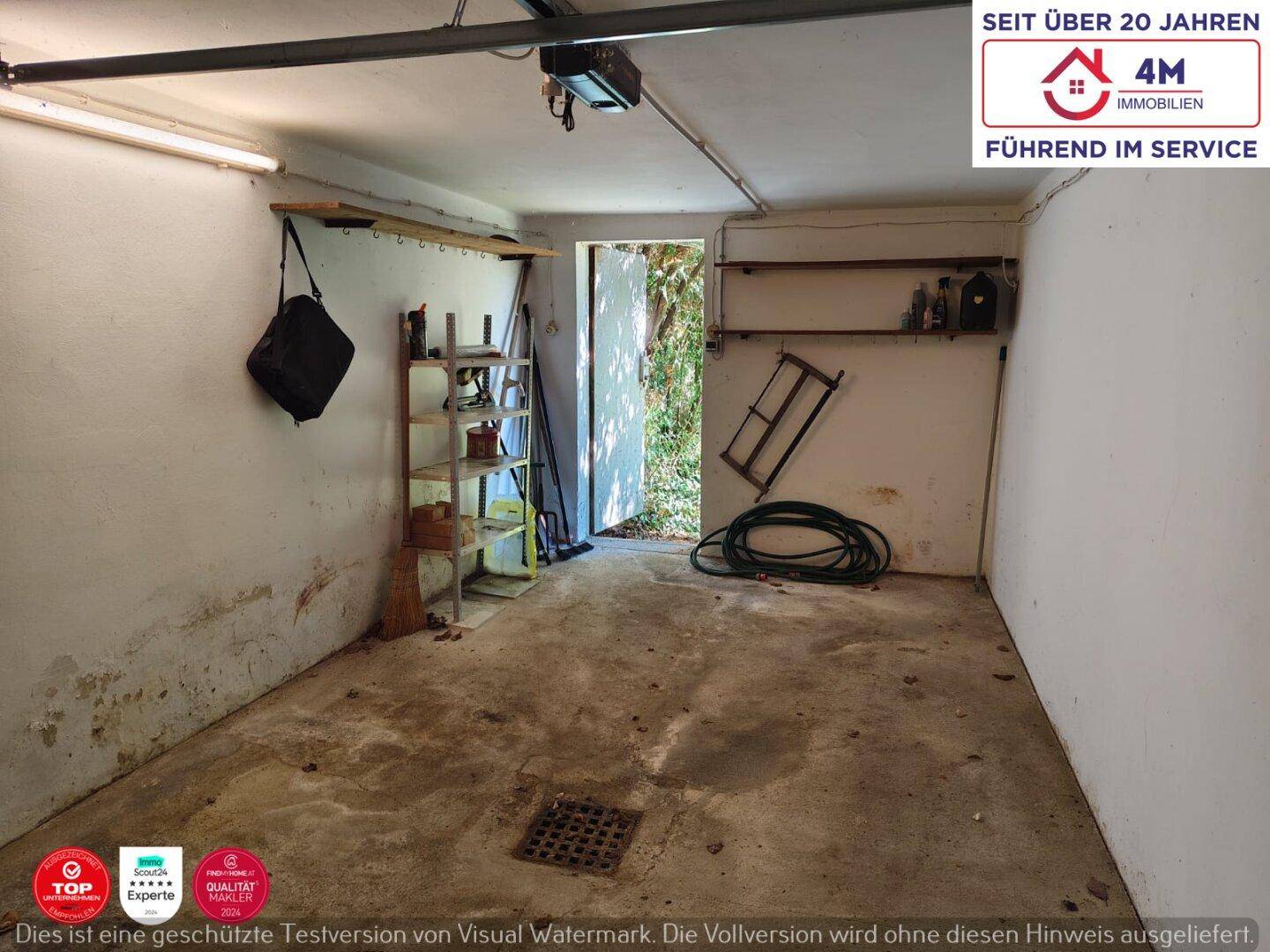 Geräumige Garage mit Betonboden, Regalen und Zugang zum Außenbereich.