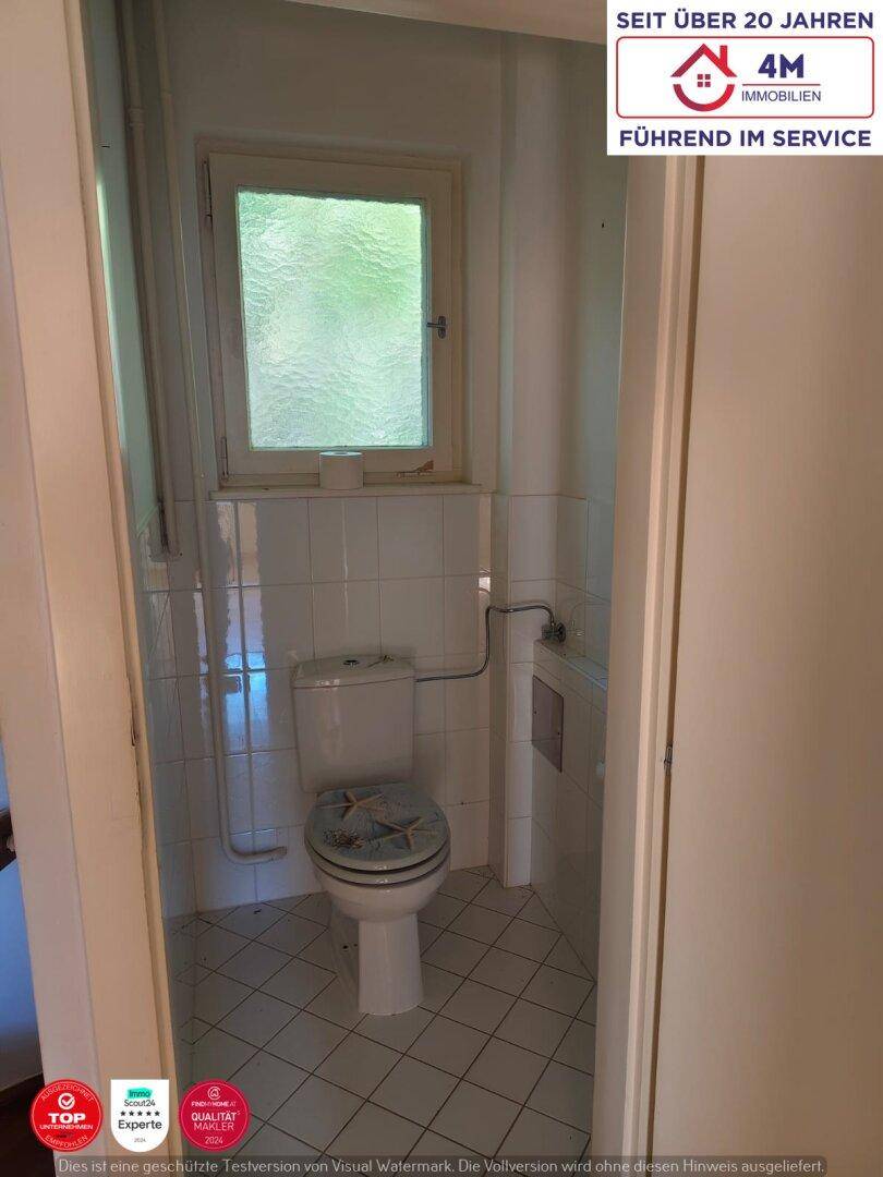 Kleines Gäste-WC mit Fenster, Toilette und weißen Fliesen.