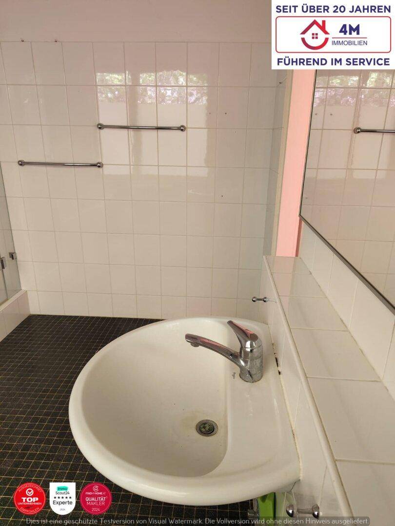 Badezimmer mit Waschbecken, Spiegel und weißen Wandfliesen, funktional gestaltet.