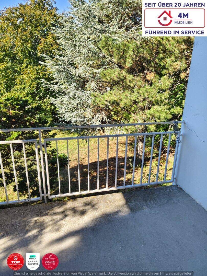 Balkon mit weißem Geländer und Blick auf die umliegende grüne Natur.