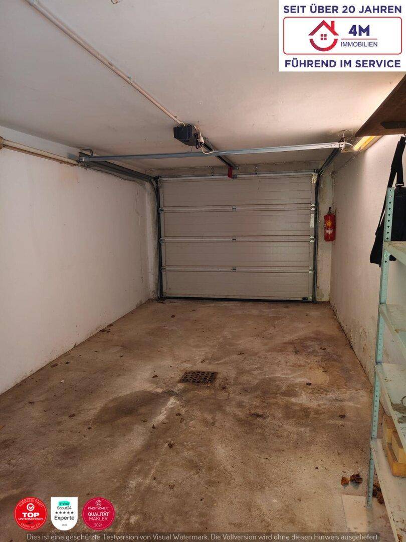 Geräumige Garage mit Rolltor und Betonboden, bereit zur Nutzung.