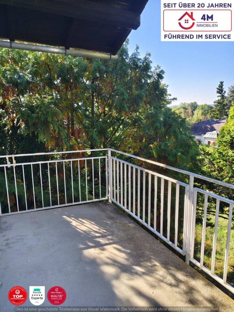 Balkon mit weißem Geländer und weitem Blick auf Bäume und die Umgebung.