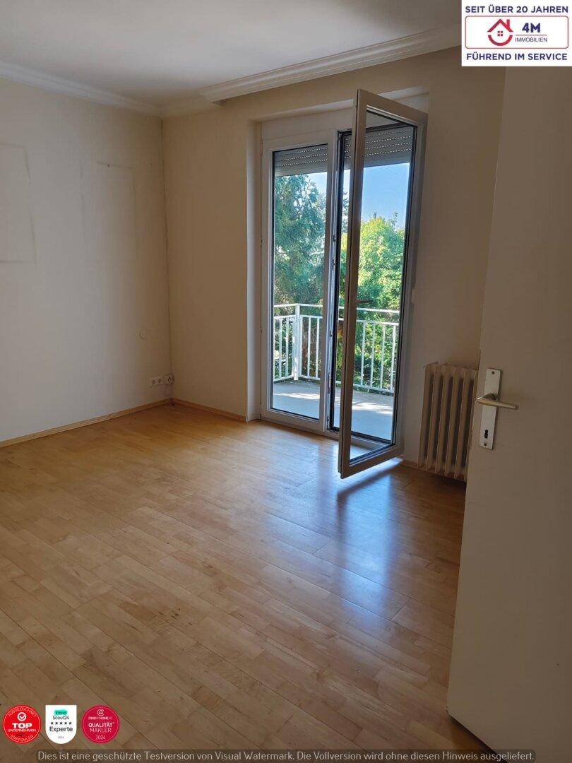 Ein helles Schlafzimmer mit Parkettboden und Zugang zu einem kleinen Balkon.