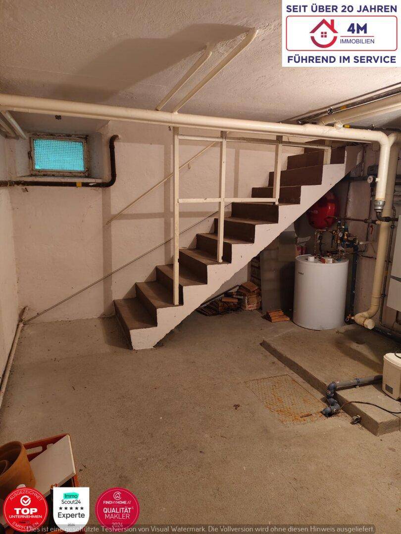 Ein Kellerraum mit einer Treppe, Heizungsanlage und sichtbaren Rohren an der Decke.