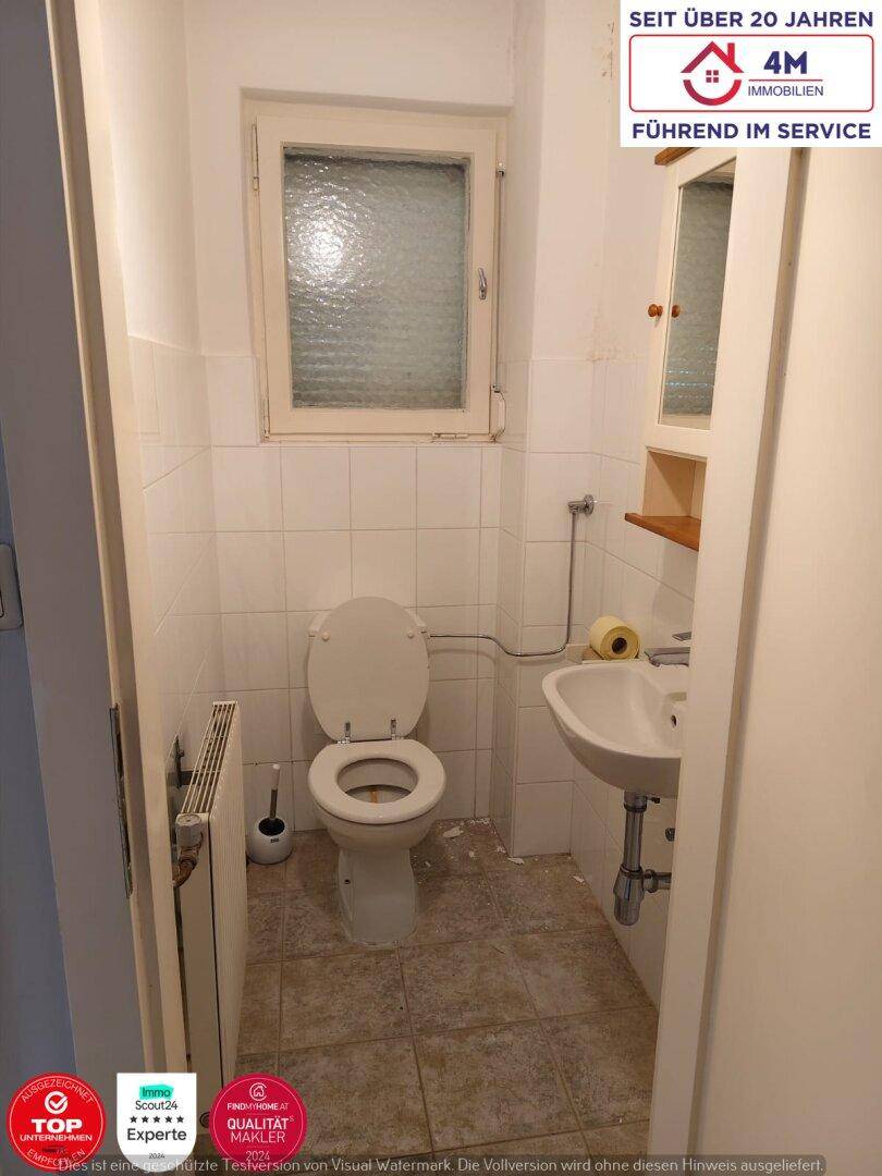 Eine kleine Gästetoilette mit Fenster, WC und Waschbecken, einfach gefliest.