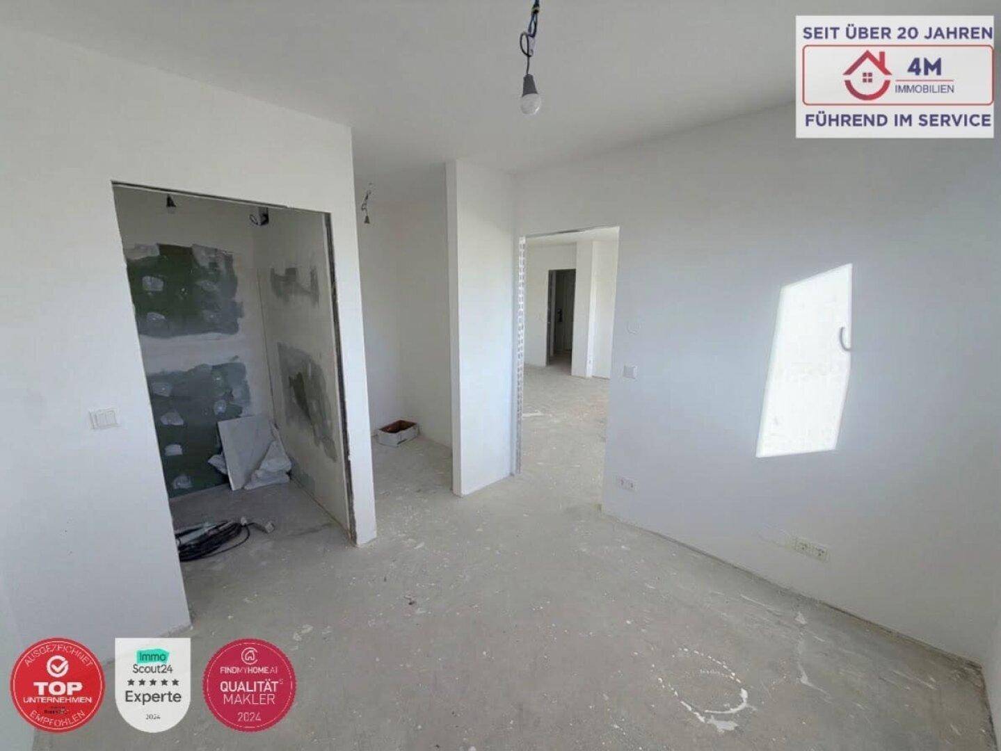 Unfertiger Flurbereich mit Rohbauwänden und Durchgängen zu weiteren Räumen im Neubau.