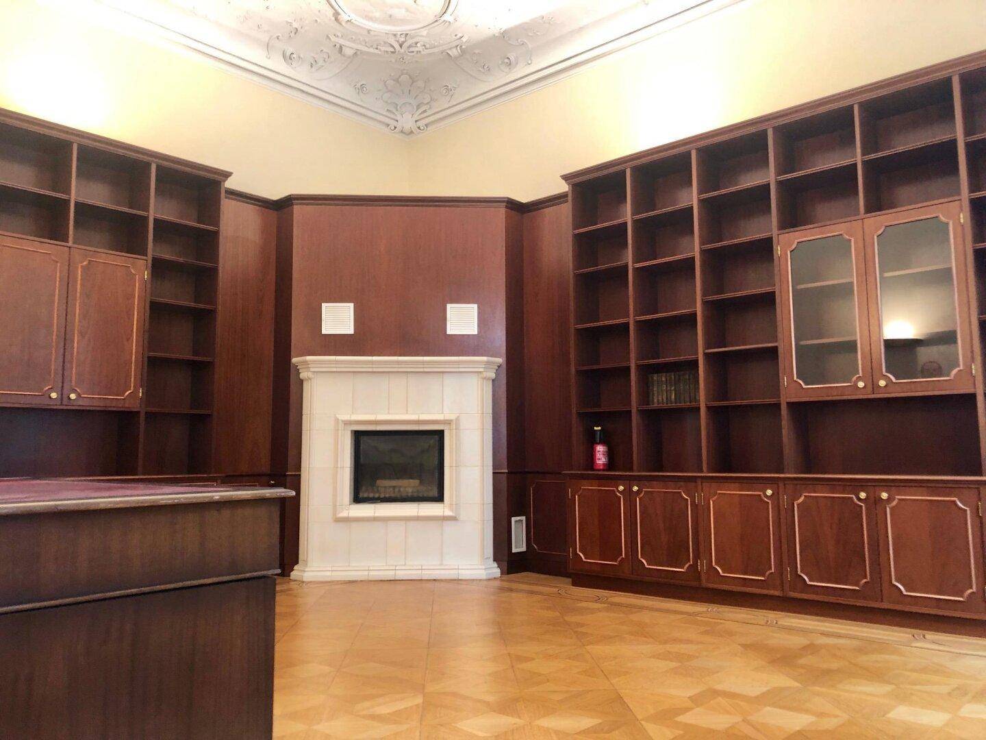 Bibliothek oder Arbeitszimmer mit maßgefertigten Holzregalen, Kamin und Stuckdecke.