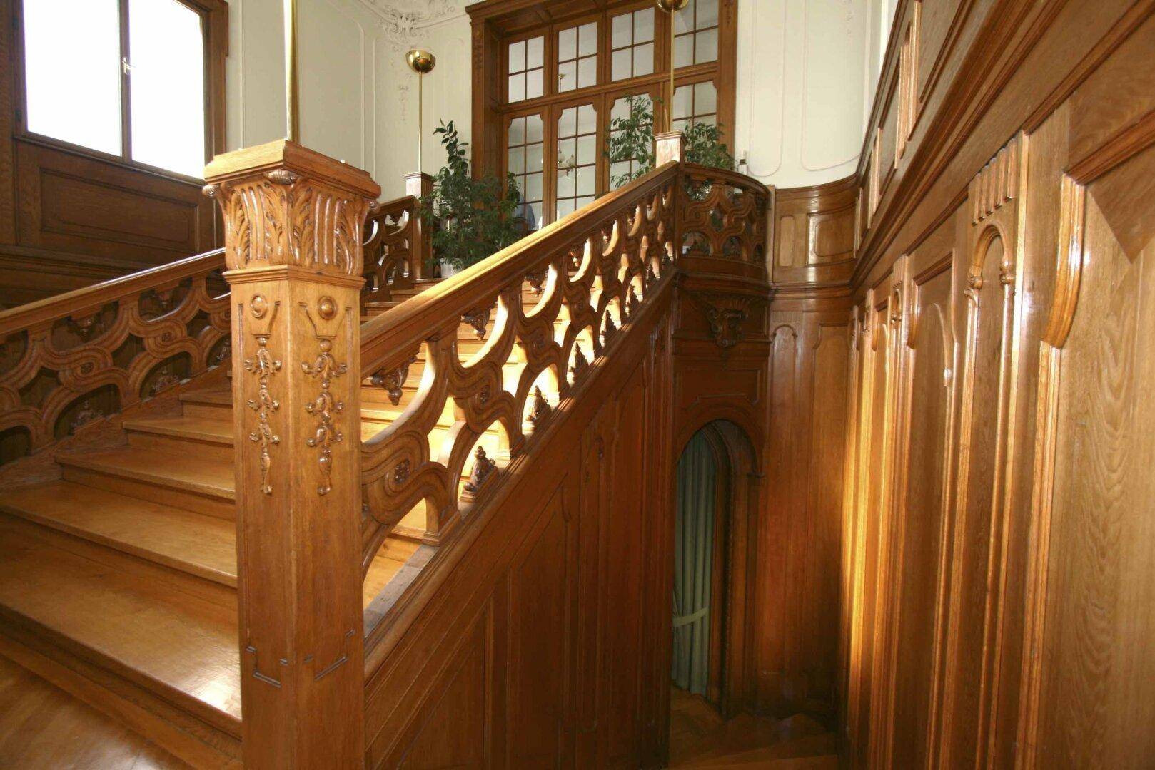 Detailansicht des historischen Holztreppenhauses mit aufwendigen Schnitzereien und Verzierungen.