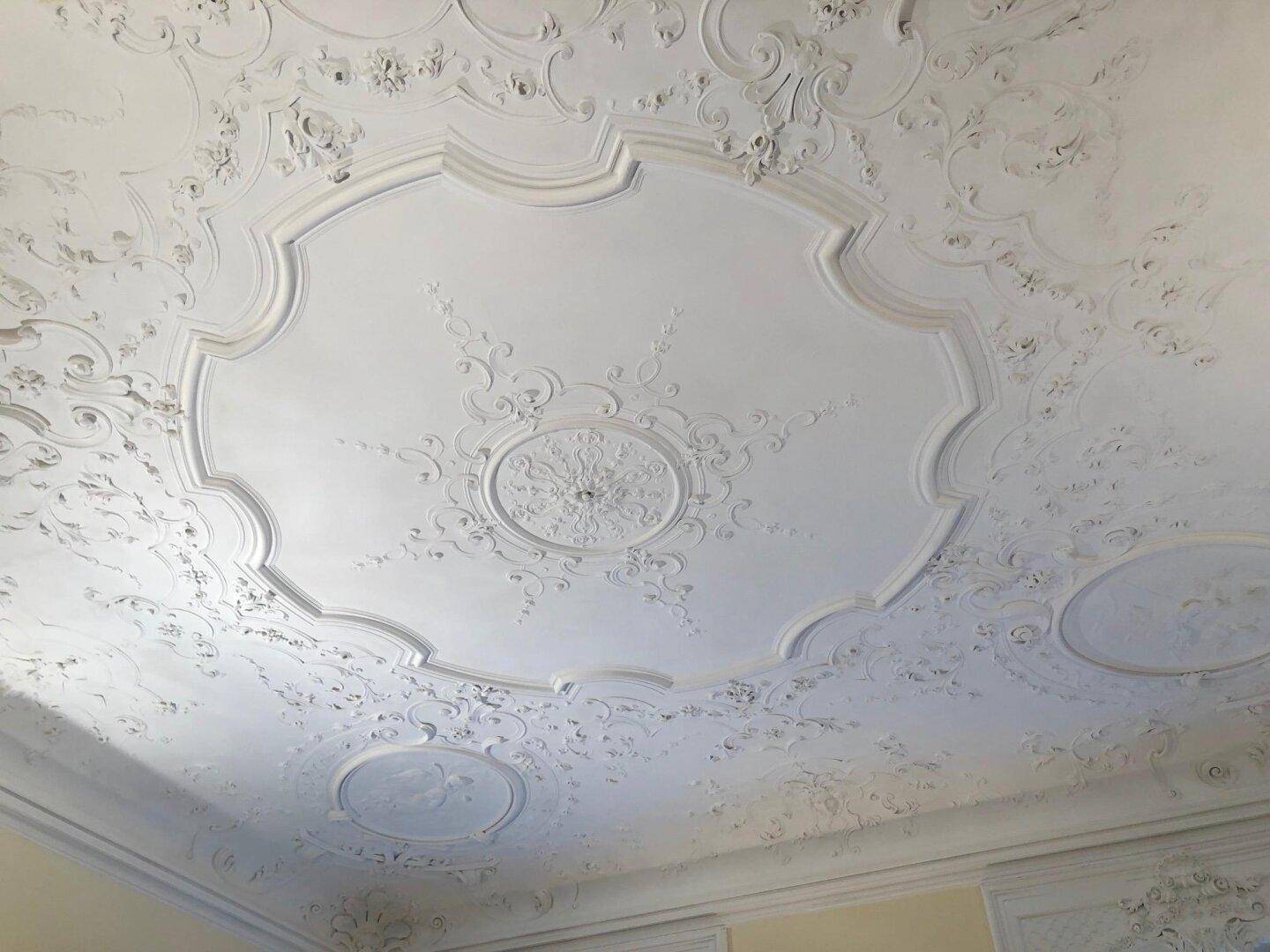 Prächtige weiße Stuckdecke mit detaillierten Ornamenten und Verzierungen.