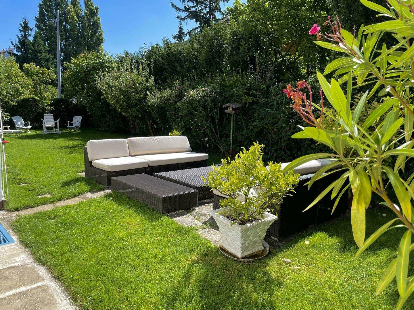 Gartenbereich mit moderner Lounge-Sitzgruppe und gepflegter Hecke im Hintergrund für Privatsphäre.