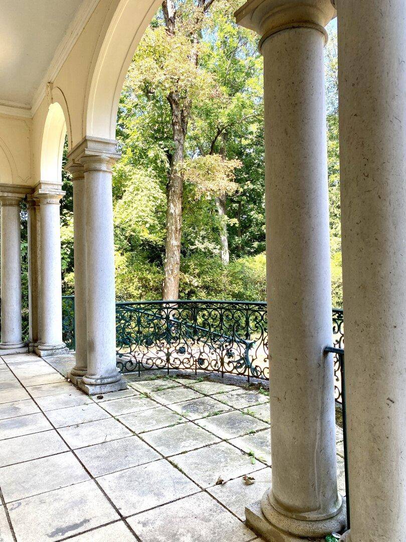 Elegante überdachte Terrasse mit klassischen Säulen und einem weiten Blick ins Grüne.