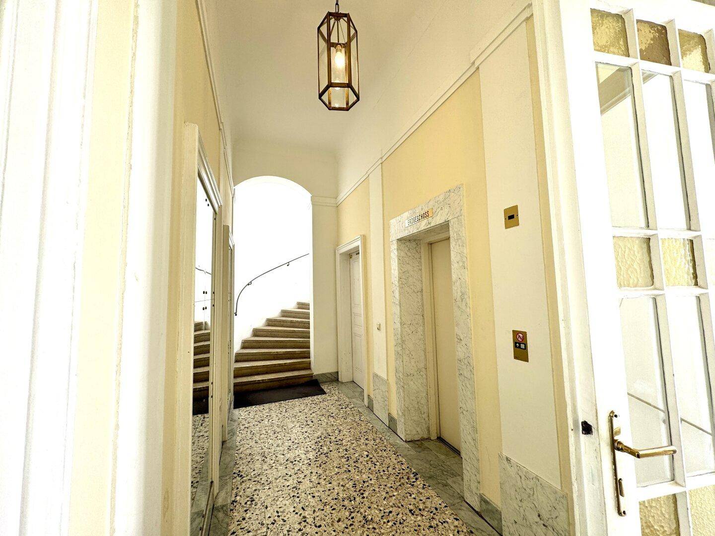 Repräsentativer Eingangsbereich mit Aufzug, Marmorverkleidung und elegantem Treppenaufgang.