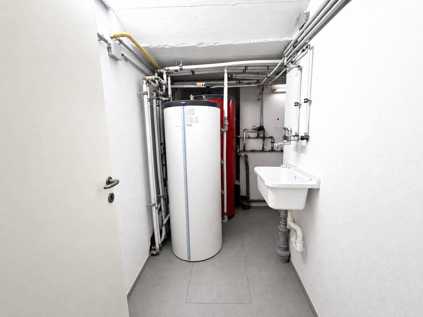Funktionaler Hauswirtschaftsraum im Keller mit Warmwasserspeichern und Waschbecken.