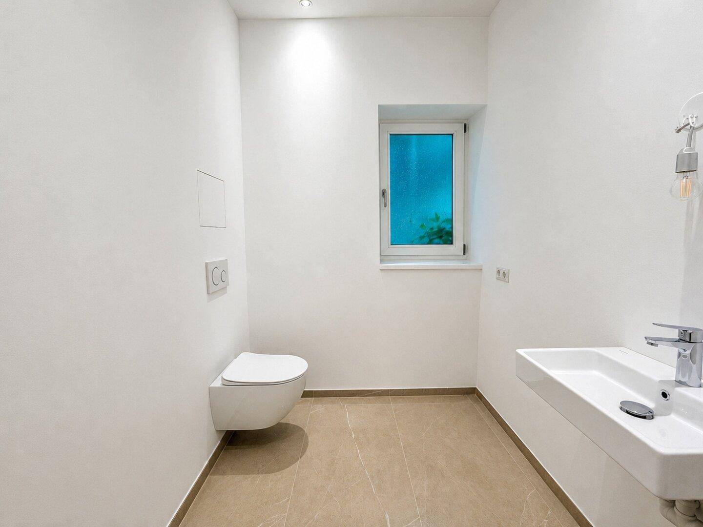 Modernes Gäste-WC mit wandhängendem WC, Waschbecken und Fenster.