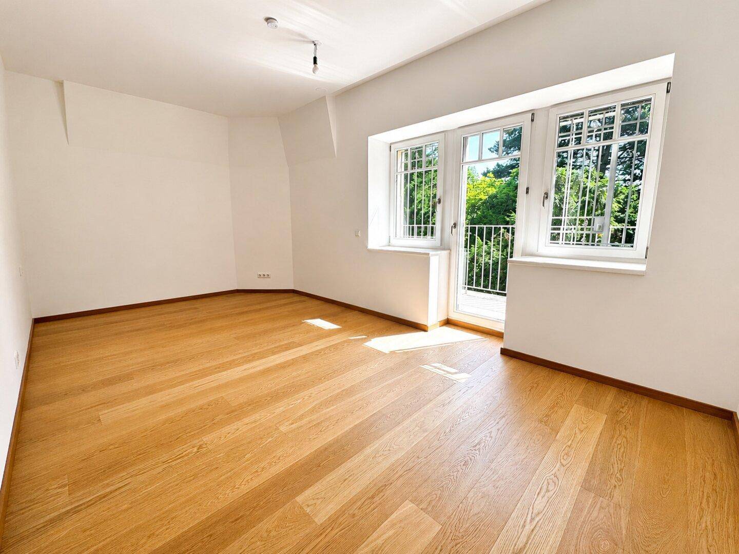 Helles Zimmer mit Eichenparkett und französischem Balkon mit Blick ins Grüne.