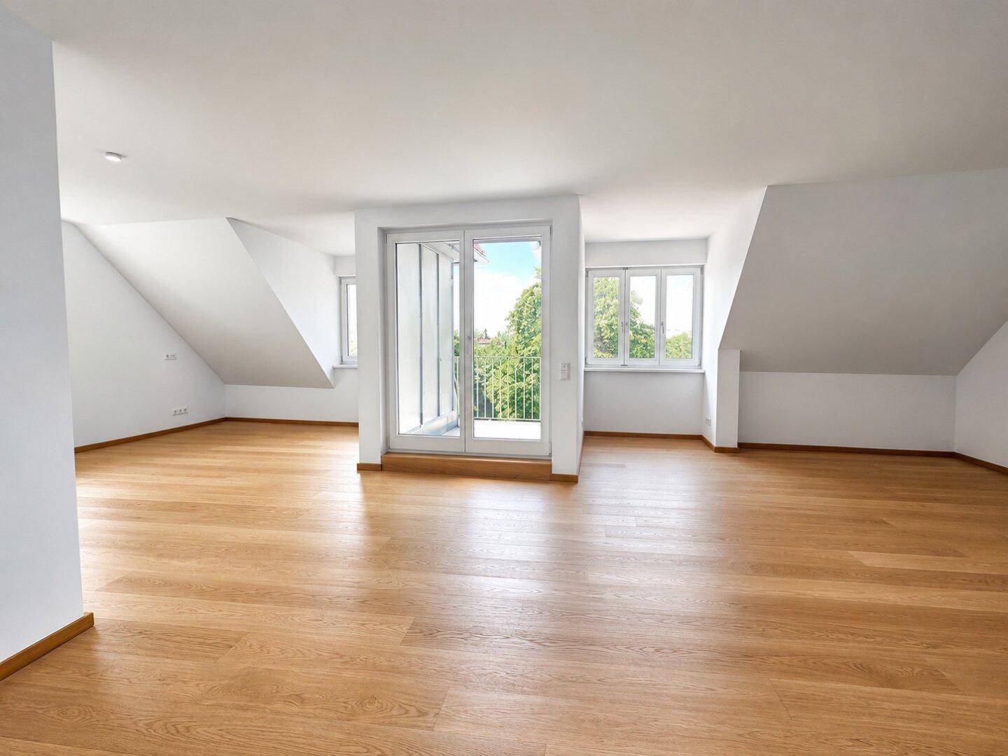 Helles Dachgeschosszimmer mit Eichenparkett und Zugang zu einem Balkon.