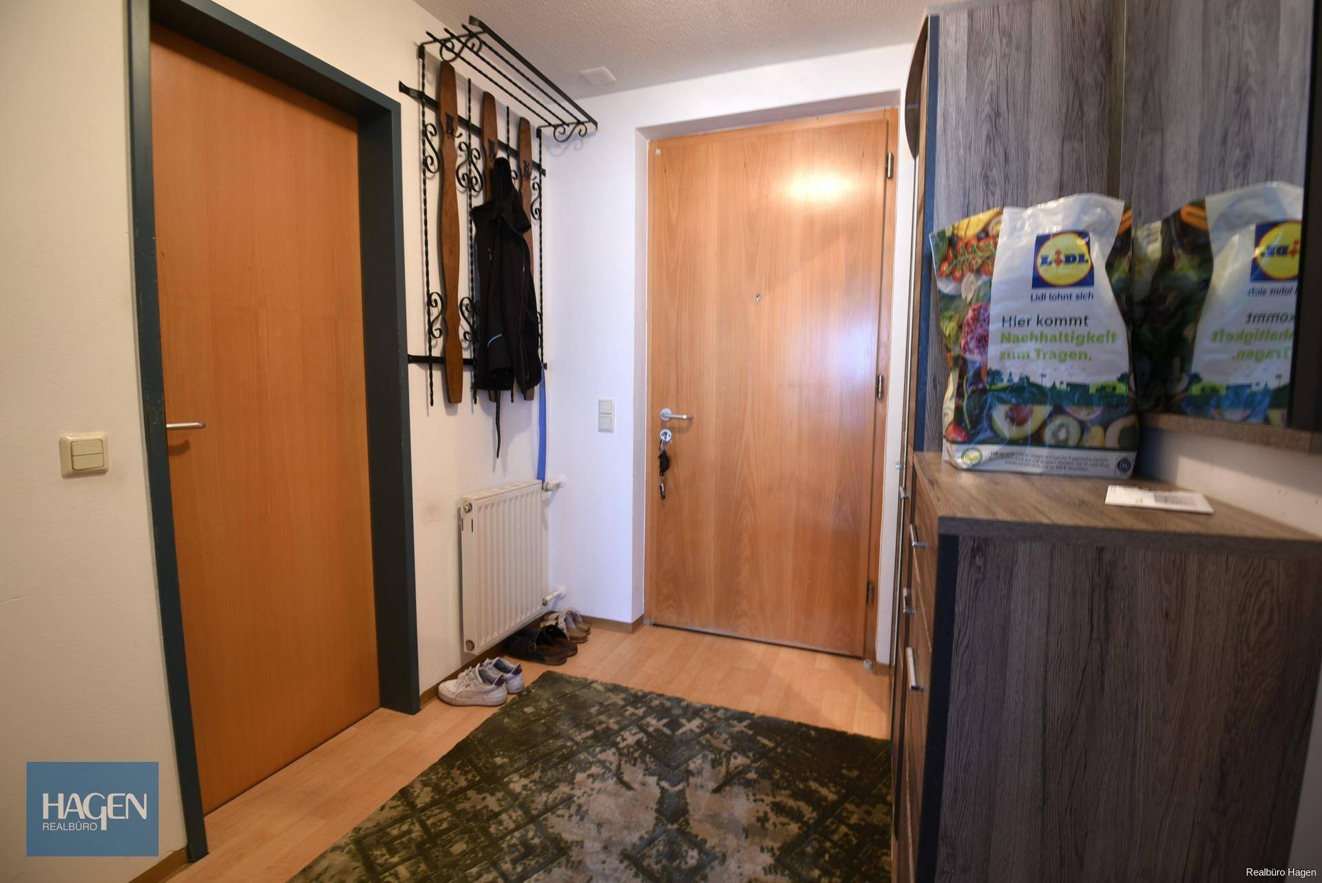 Eingangsbereich mit Garderobe, Holztüren und Teppich auf Parkettboden.