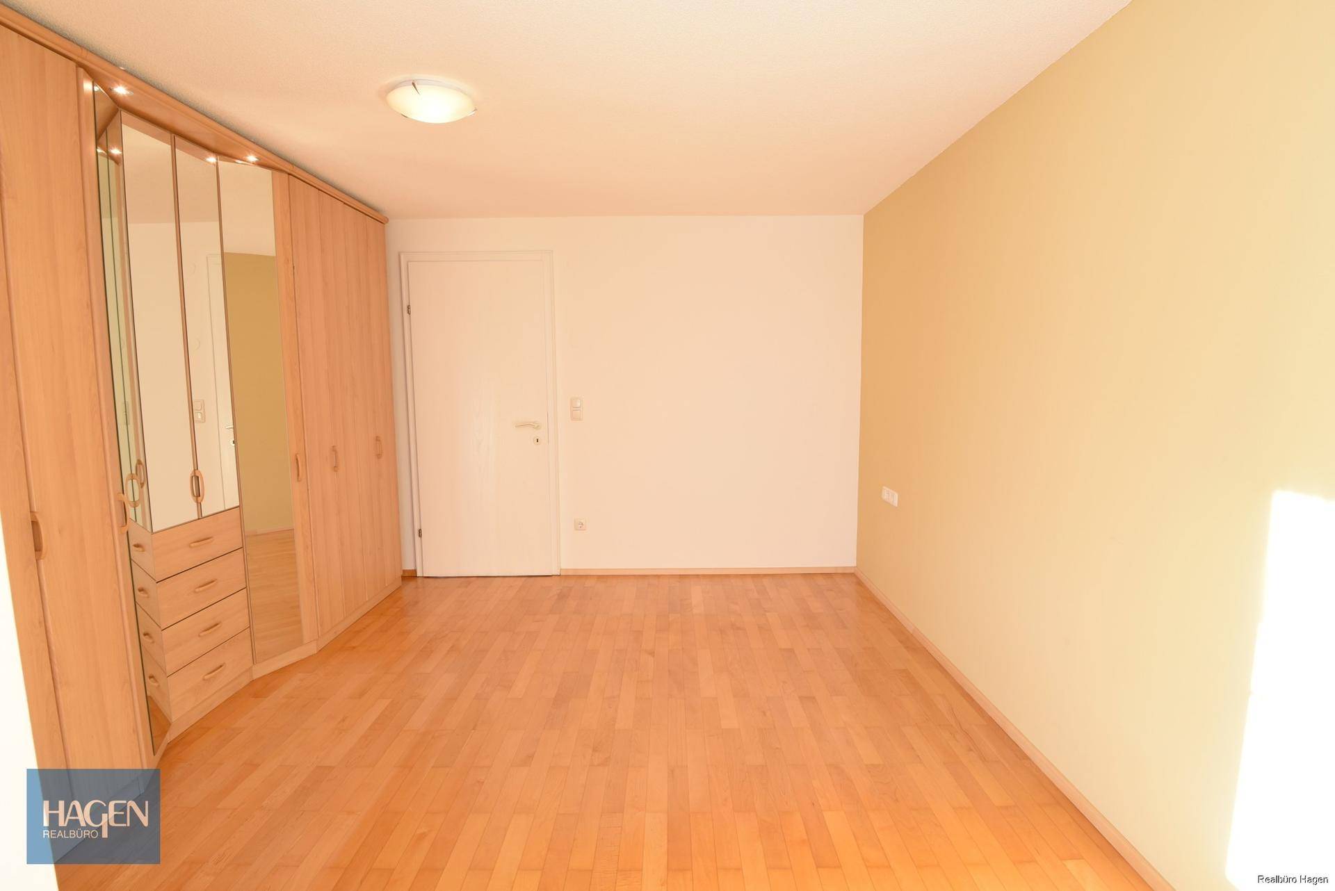 Geräumiges Schlafzimmer mit Holzboden und praktischen Einbauschränken für viel Stauraum.