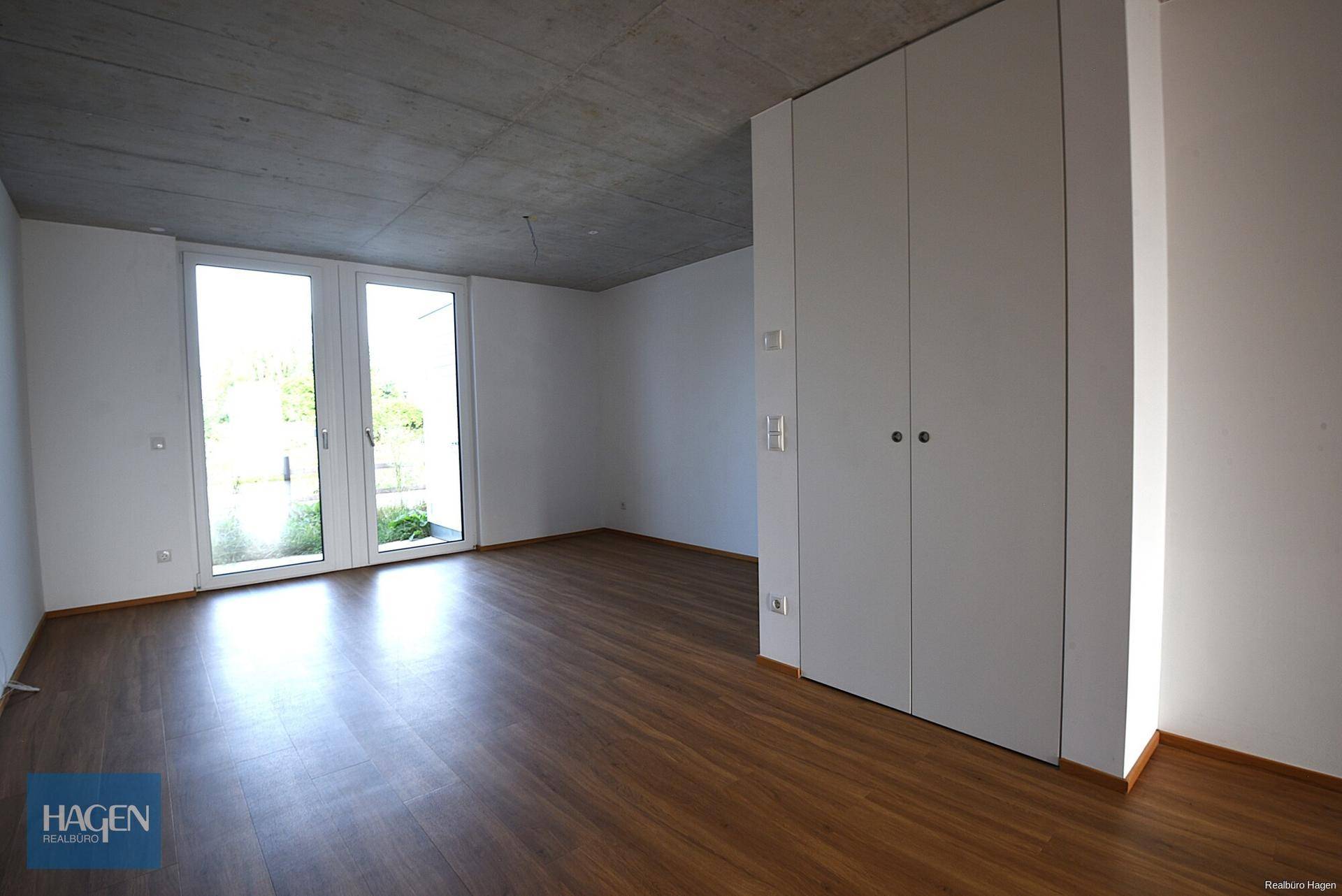 Lichtdurchfluteter Raum mit Laminatboden, hohen Decken und praktischen Einbauschränken.