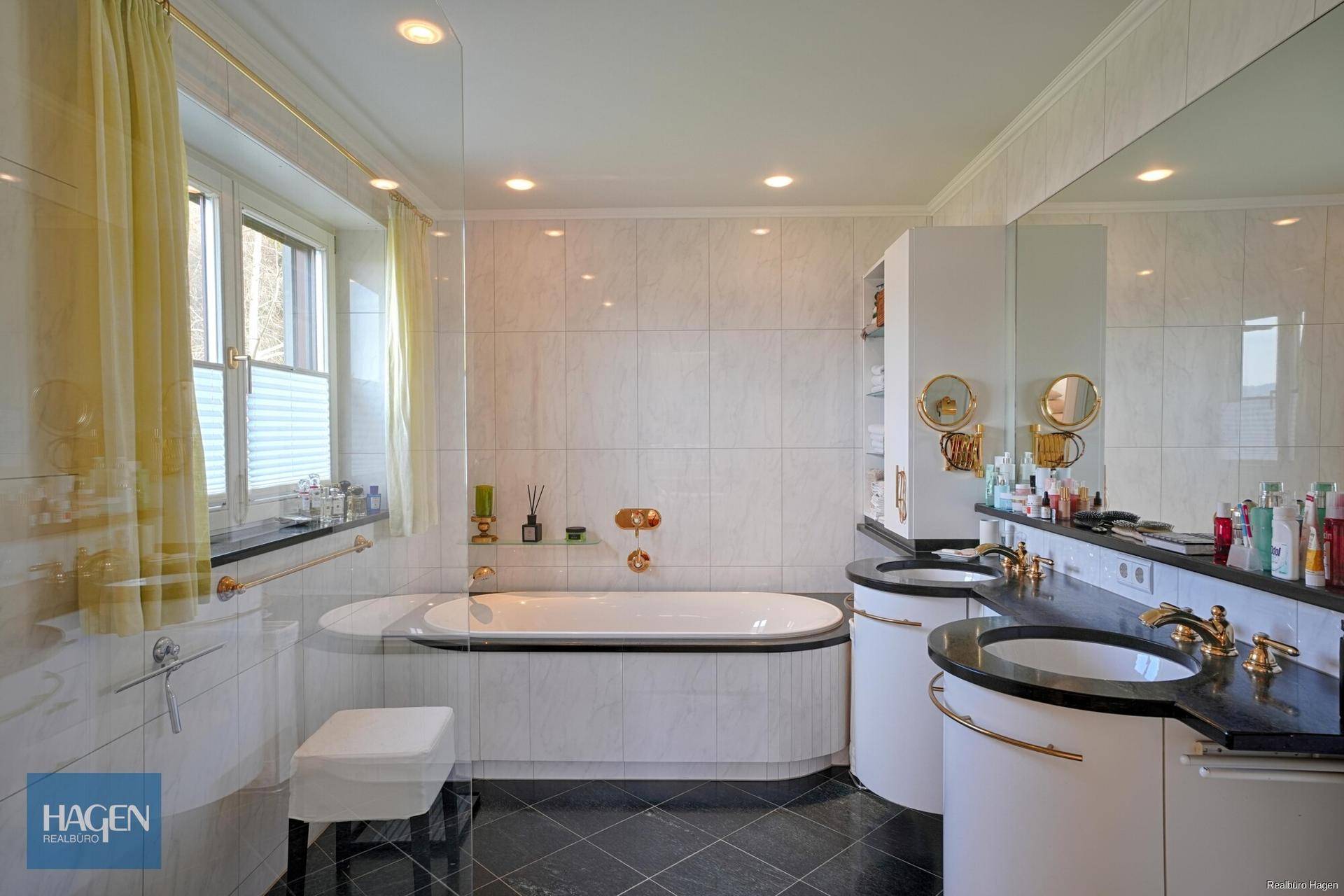 Elegantes Badezimmer mit Doppelwaschbecken, Badewanne und dunklen Granitflächen.