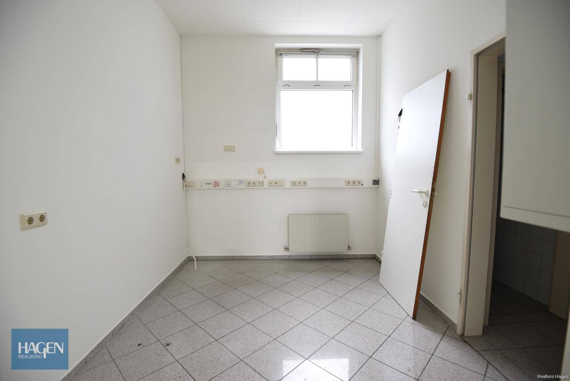 Kleiner Raum mit Fenster, vielen Steckdosen und Fliesenboden, möglicherweise für eine Teeküche oder Lager.