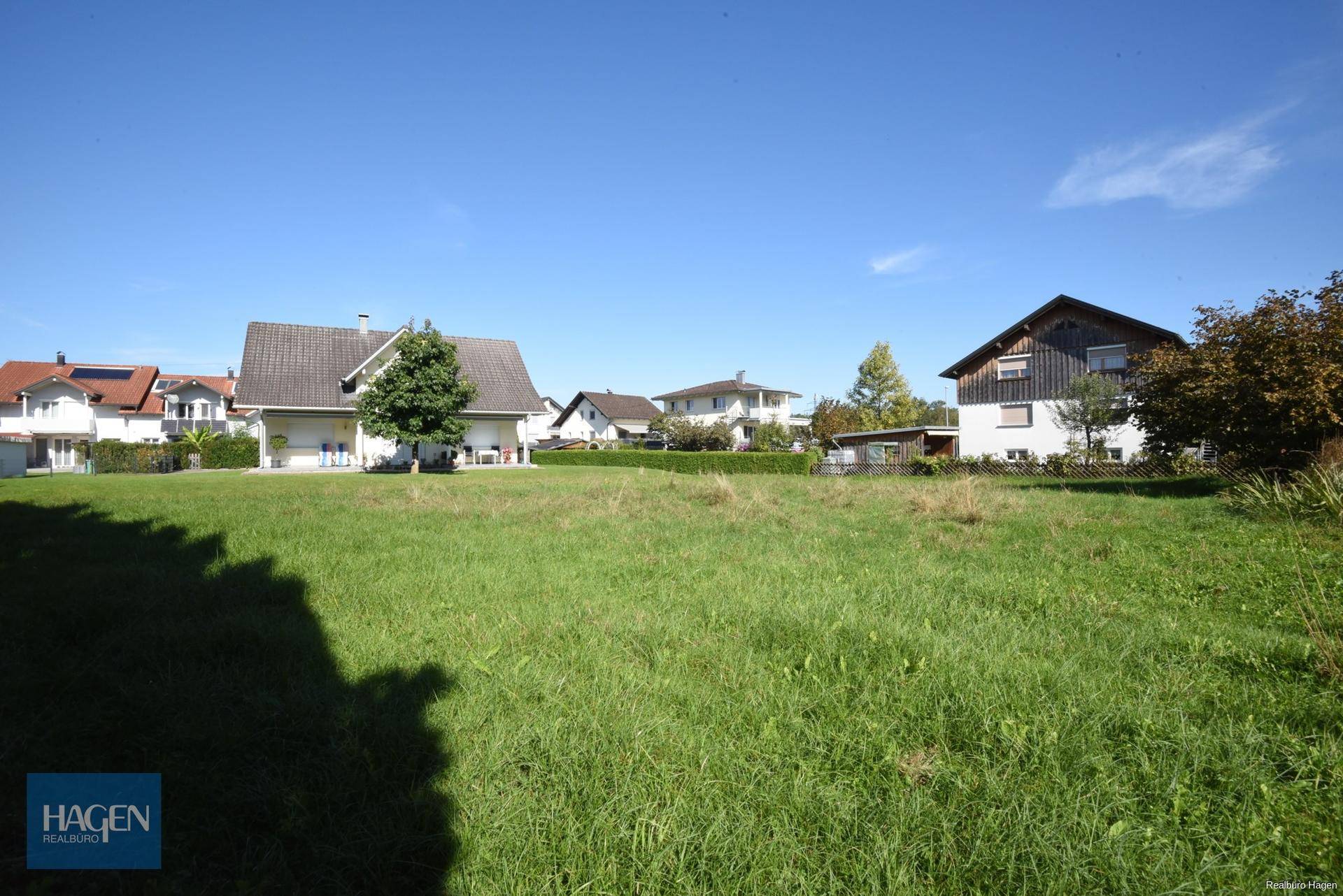 Offenes Wiesengrundstück mit Blick auf die umliegende Wohnbebauung und grüne Umgebung.
