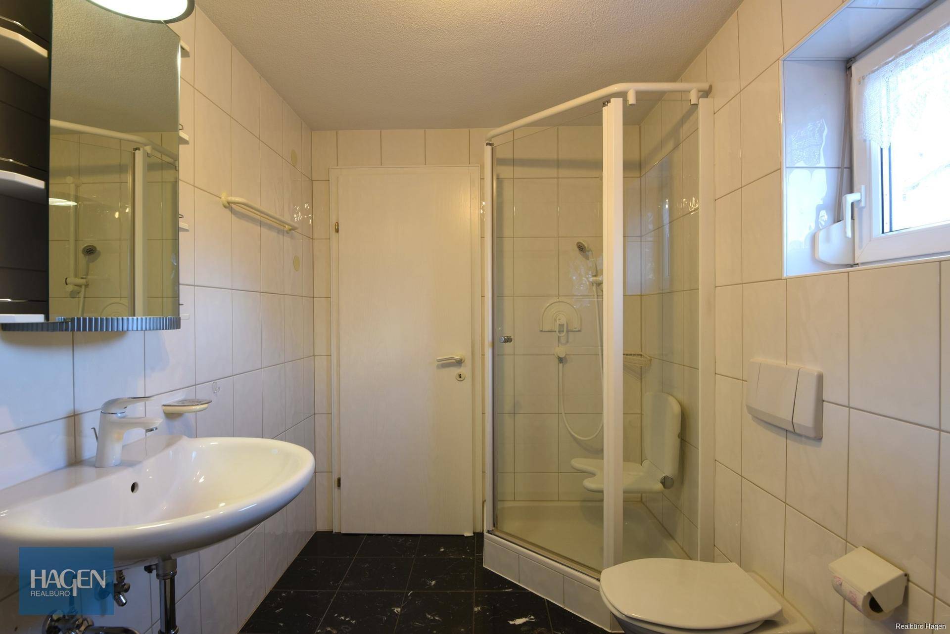 Funktionales Badezimmer mit Dusche, WC, Waschbecken und Fenster für natürliche Belüftung.