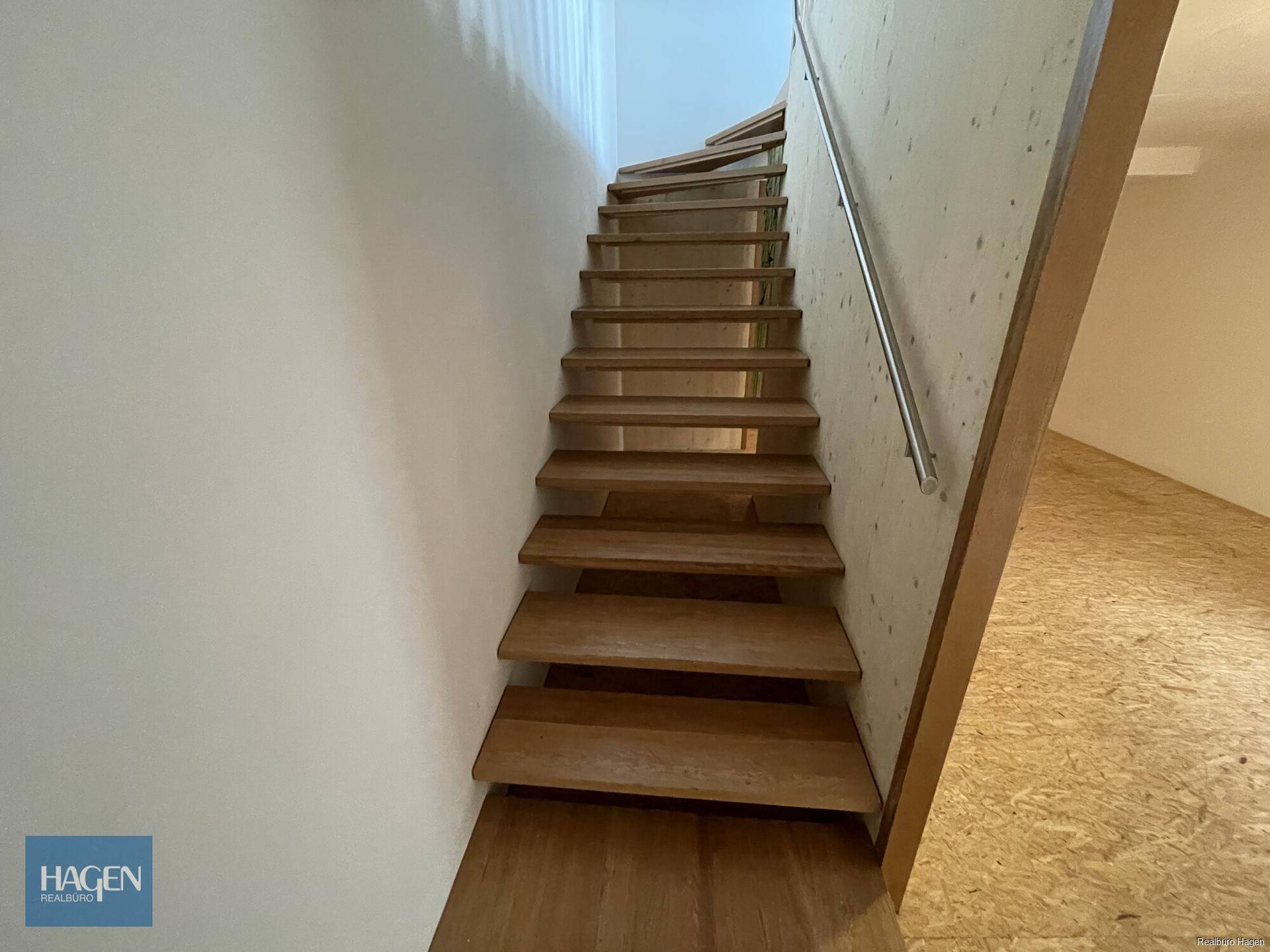 Moderne Holztreppe mit Metallgeländer, die verschiedene Ebenen des Hauses verbindet.