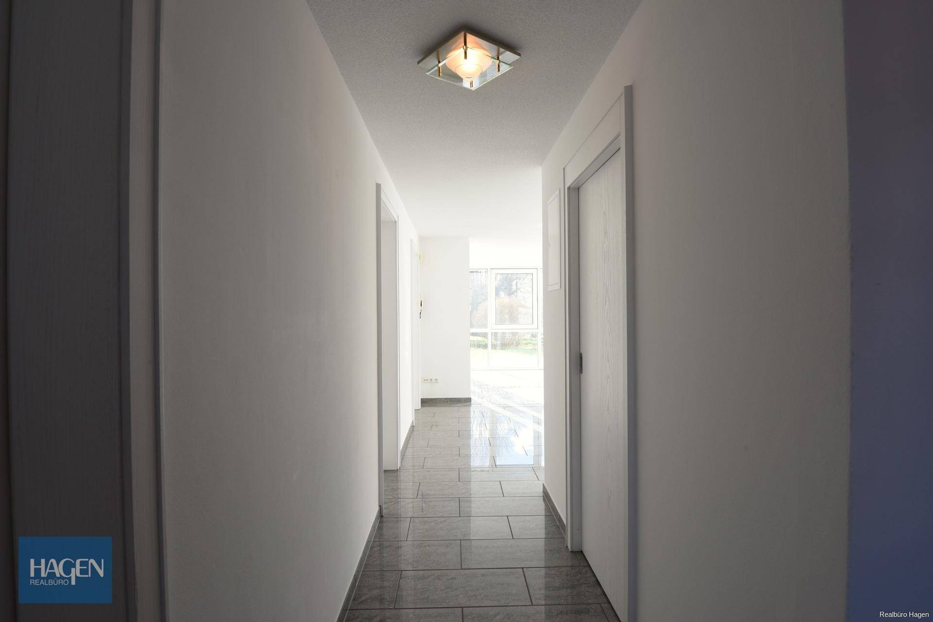 Heller Flur mit Fliesenboden, der zu den verschiedenen Räumen der Wohnung führt.