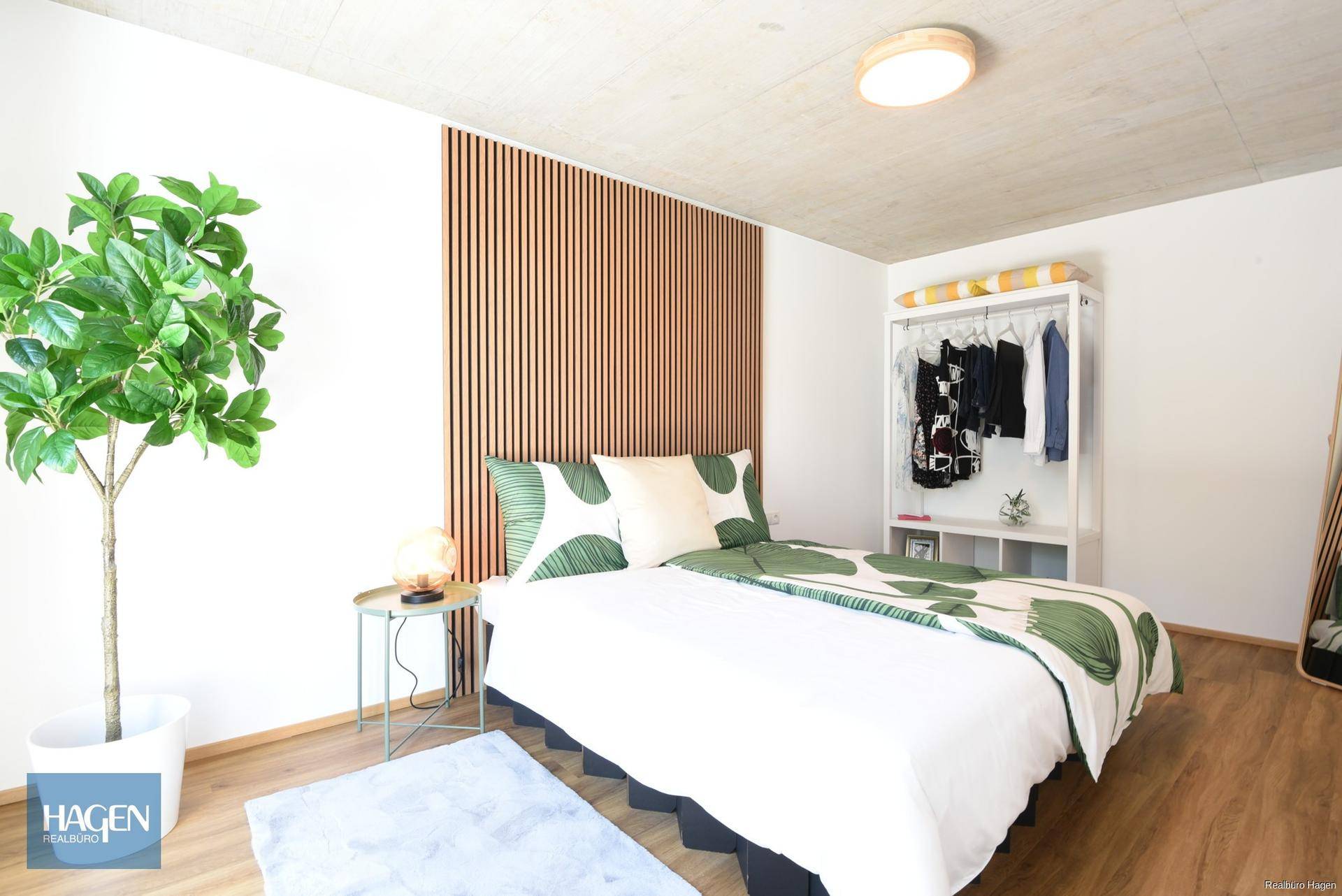 Schlafzimmer mit Holzboden, modernem Bett und dekorativer Holzvertäfelung an der Wand.
