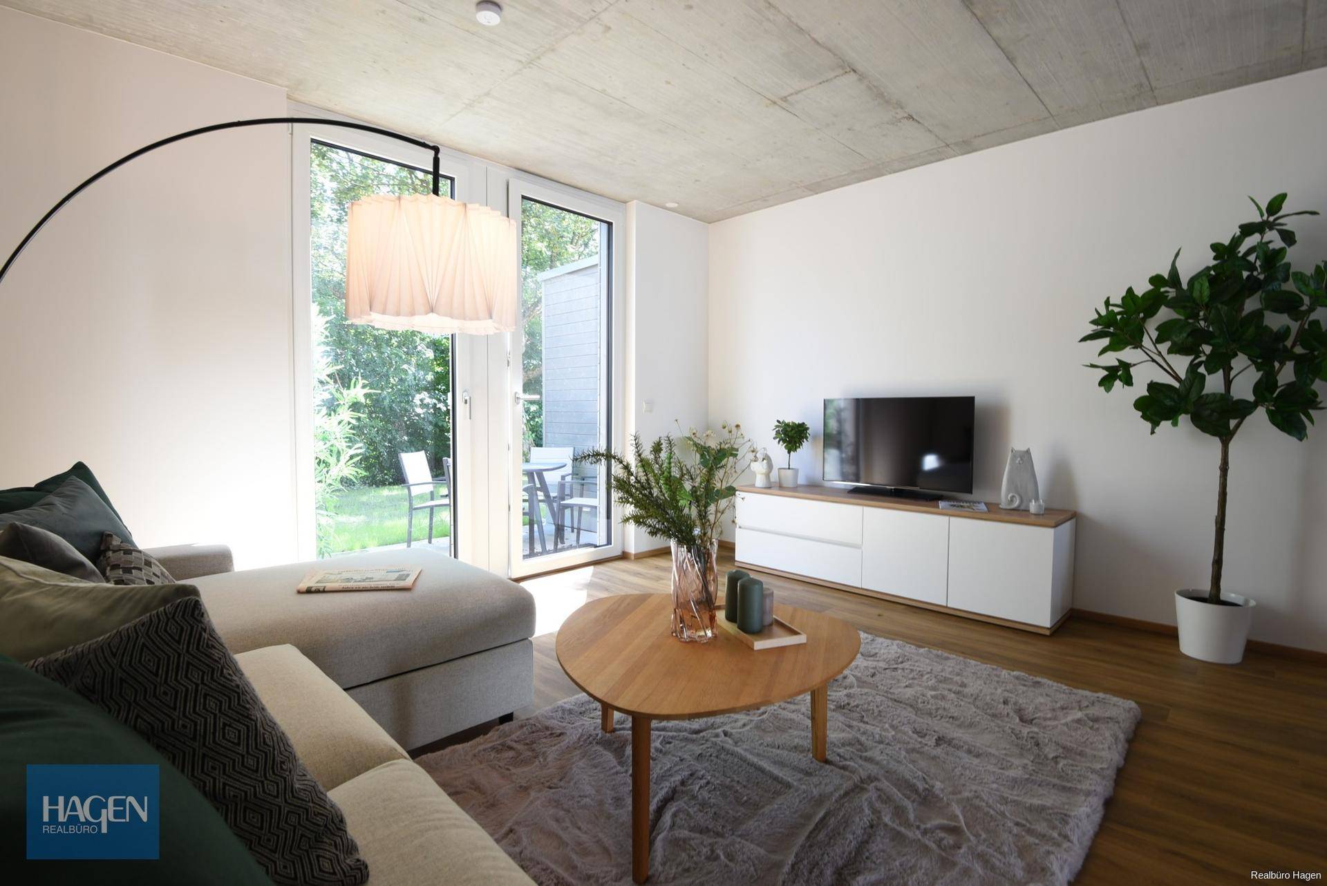 Gemütliches Wohnzimmer mit Sofa, Couchtisch und Blick durch die Terrassentür in den Garten.