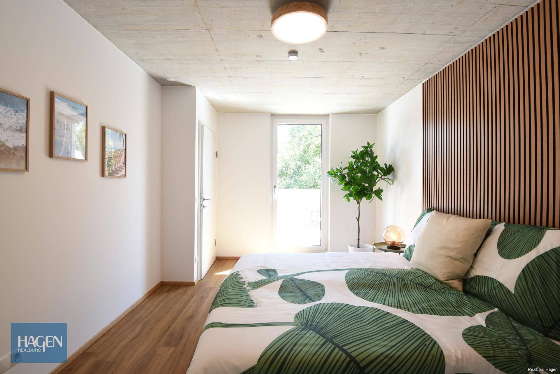 Helles Schlafzimmer mit Holzboden, modernem Bett und Zugang zu einem Balkon oder Terrasse.