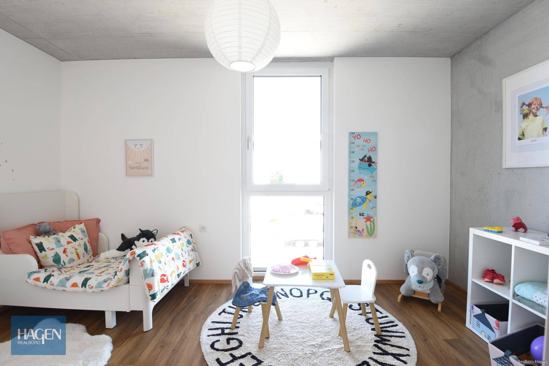 Helles Kinderzimmer mit kleinem Tisch, Stühlen und Bett, ideal zum Spielen und Lernen.