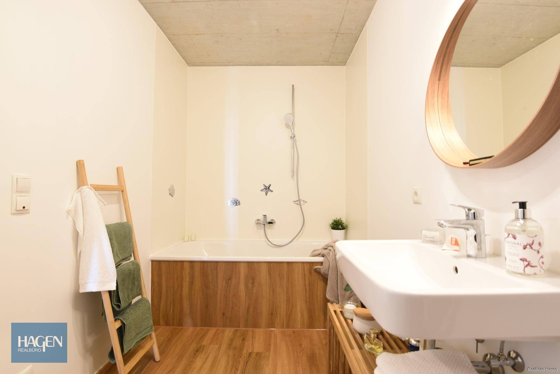 Modernes Badezimmer mit Badewanne, Waschbecken und Holzverkleidung, hell und funktional.
