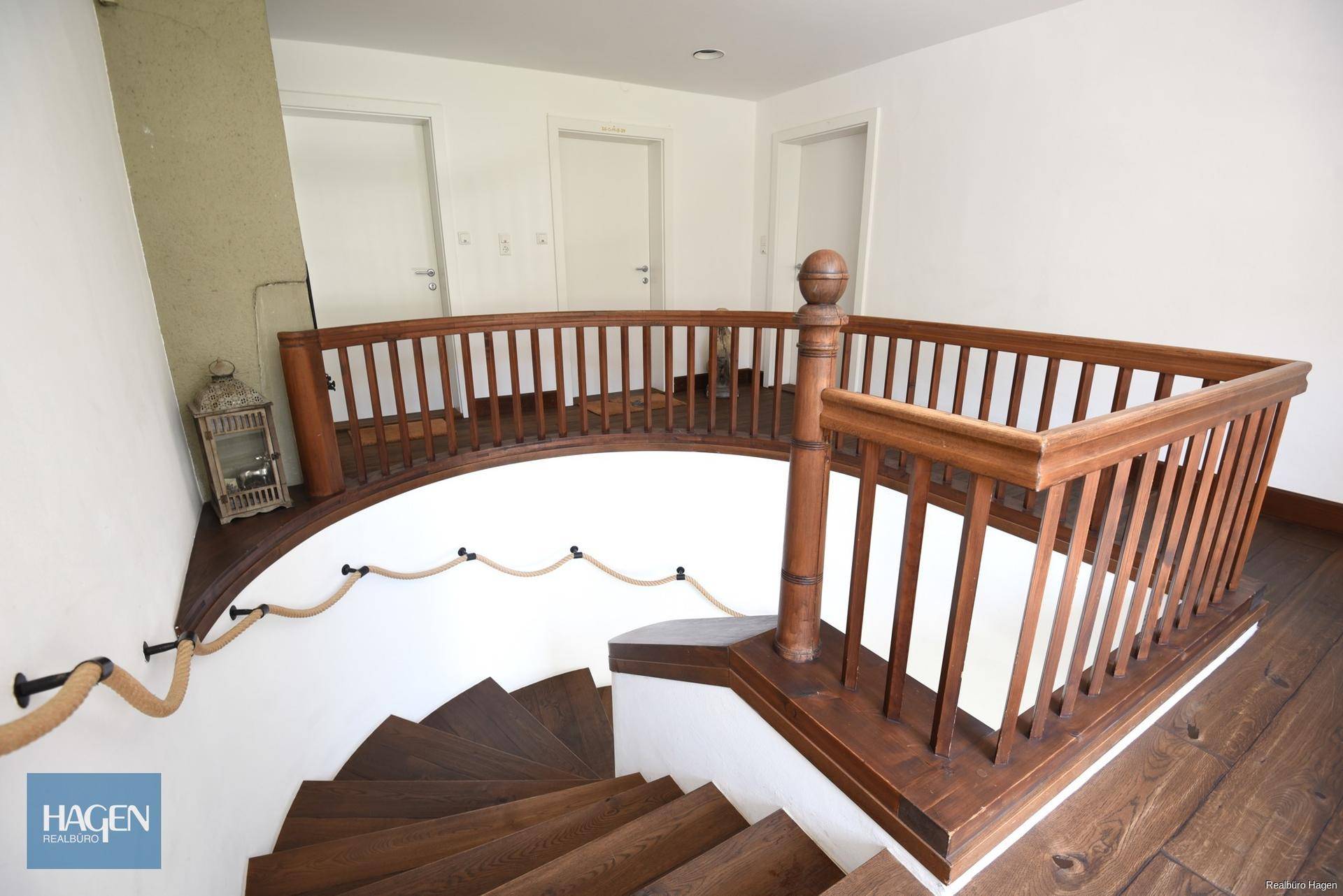 Elegantes Treppenhaus mit Holzgeländer und Seilhandlauf, das verschiedene Ebenen verbindet.